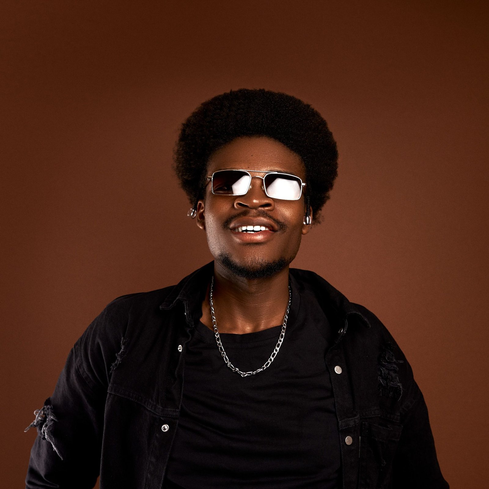 Confident African man in a fashion studio wearing sunglasses and a black outfit.